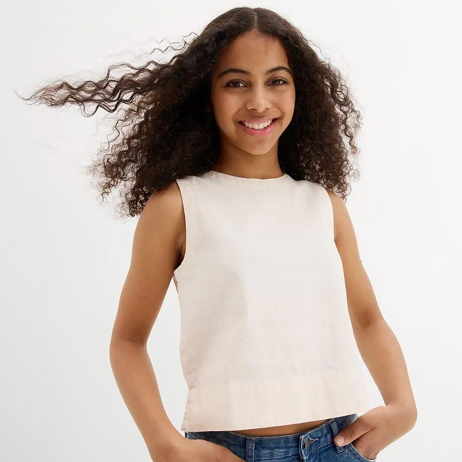 Hellbeiges &auml;rmelloses Top und blaue Jeans.