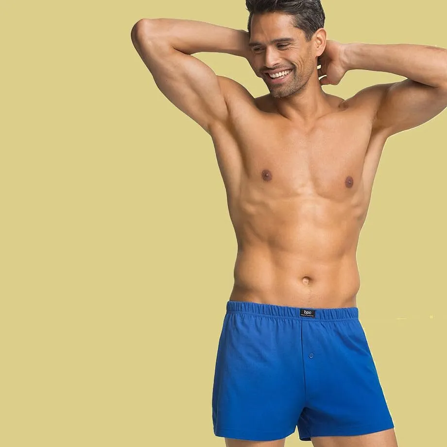Ein muskul&ouml;ser Mann tr&auml;gt blaue Boxershorts.
