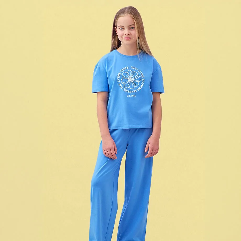 Un T-shirt bleu clair avec inscription et un pantalon bleu de coupe large assorti.