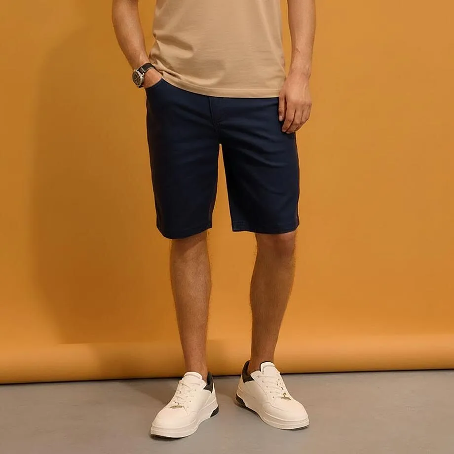 Beiges T-Shirt, dunkelblaue Shorts und wei&szlig;e Sneaker.