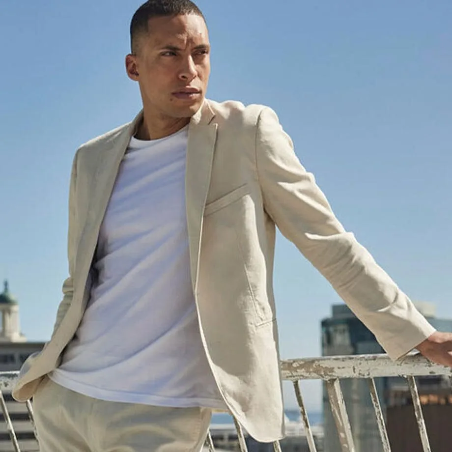 Blazer en lin de couleur claire, pantalon assorti et T-shirt blanc.