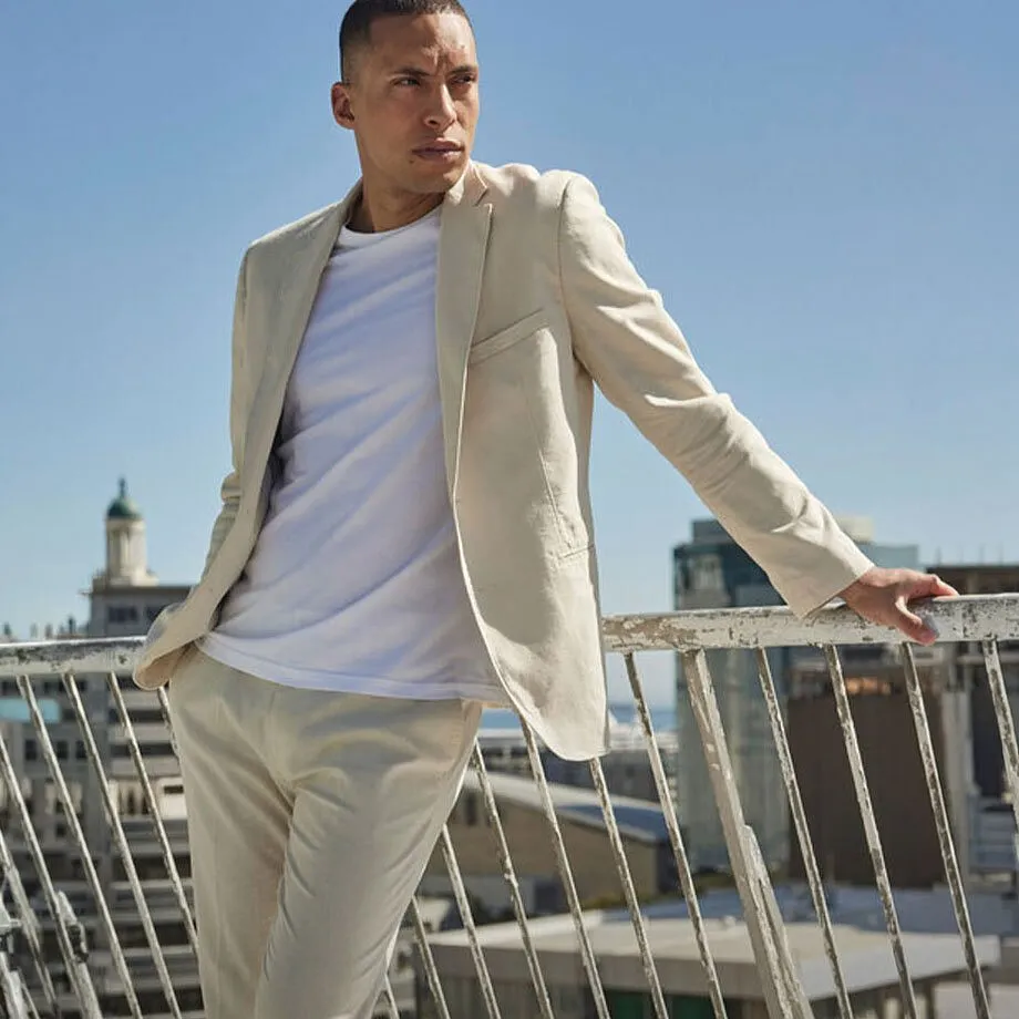 Blazer en lin de couleur claire, pantalon assorti et T-shirt blanc.