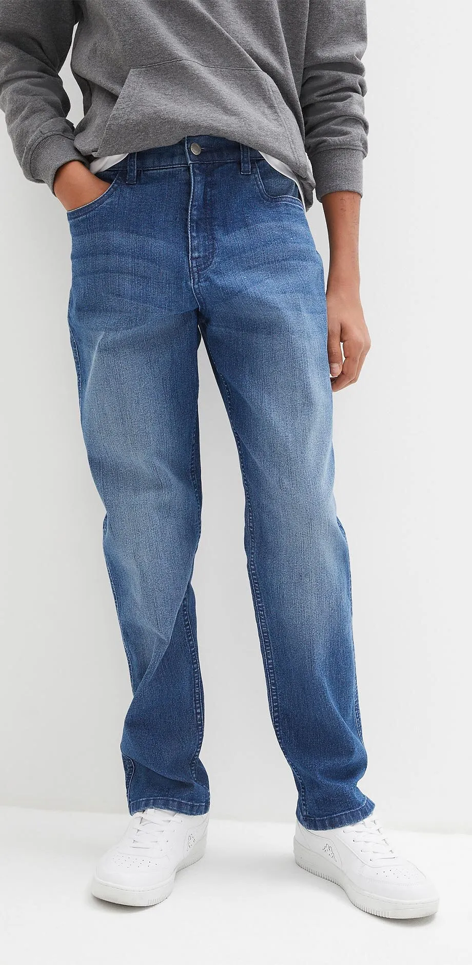 Sweat gris, jean bleu et sneakers blanches pour une tenue cool.