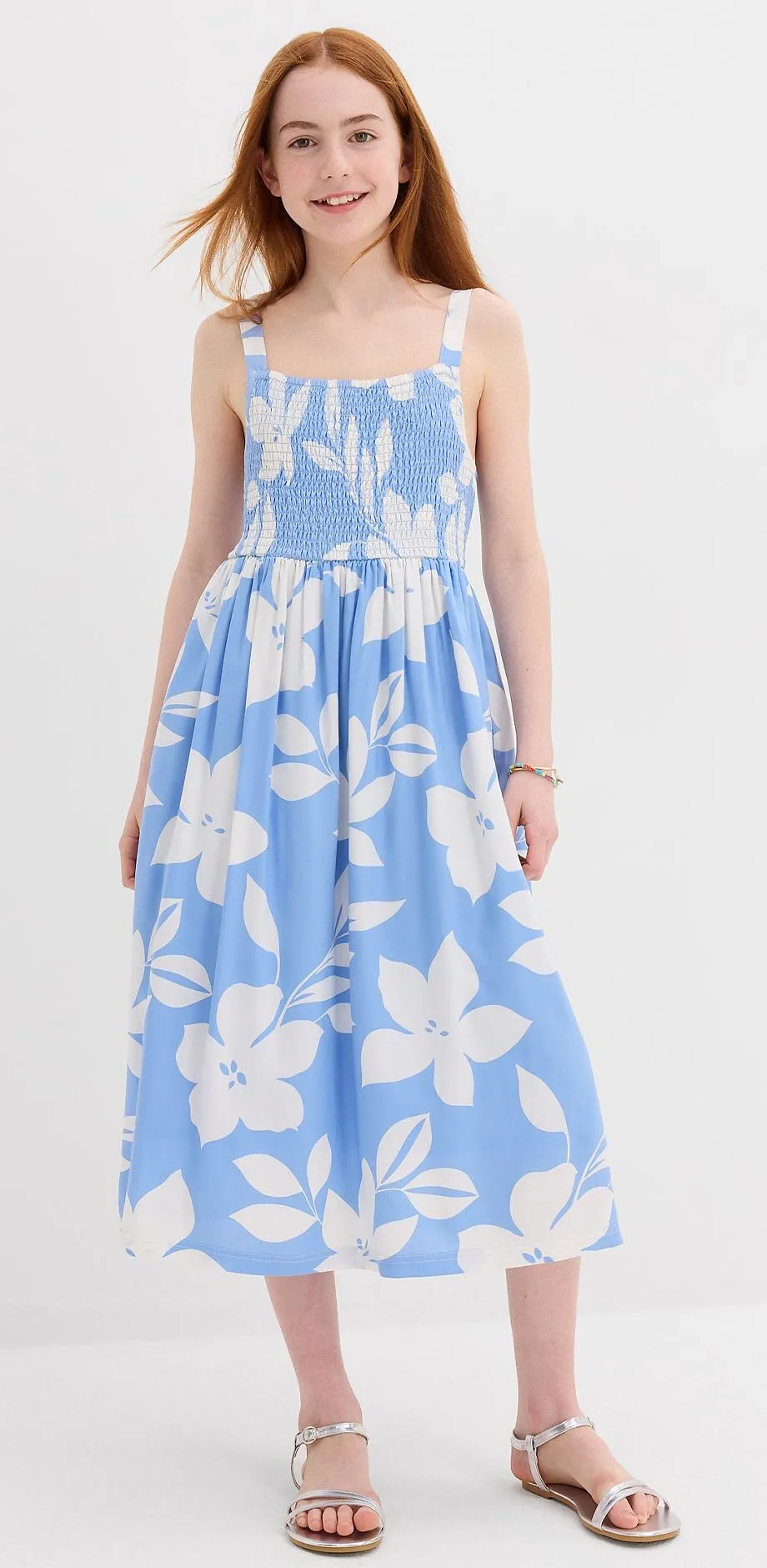 Jeune fille v&ecirc;tue d'une robe estivale bleu clair &agrave; fleurs blanches.