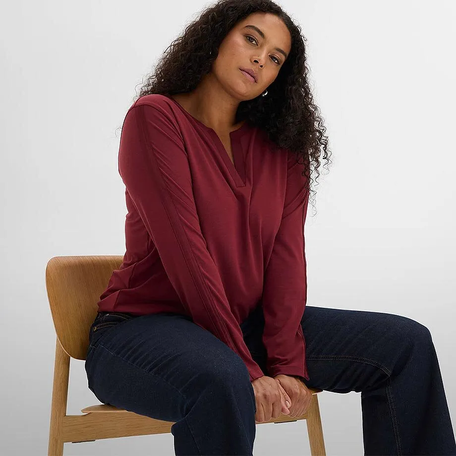 T-shirt bordeaux &agrave; manches longues et d&eacute;collet&eacute; en V et jean bleu fonc&eacute;.