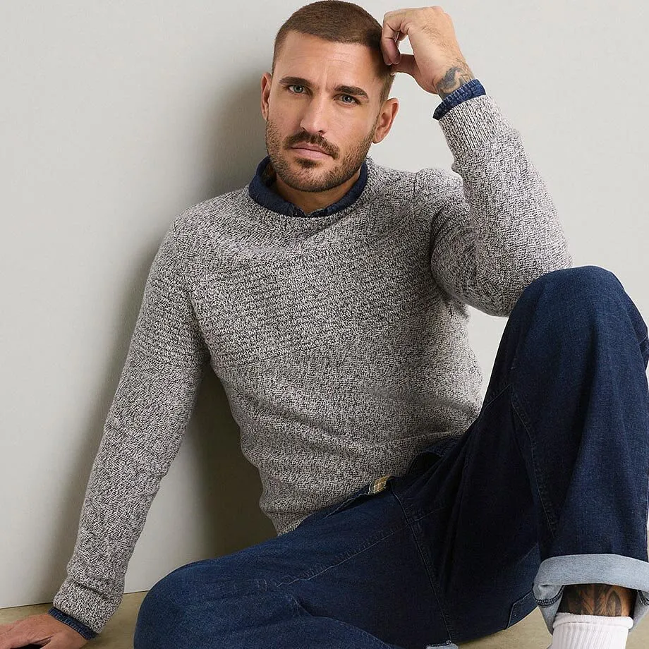 Stylischer, grober Strickpullover, Hemd darunter, kombiniert mit dunklen Jeans.