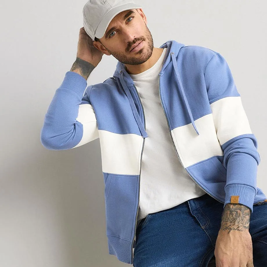 L&auml;ssiger Look: Blauer Hoodie, wei&szlig;es Shirt, Jeans und graue Cap.