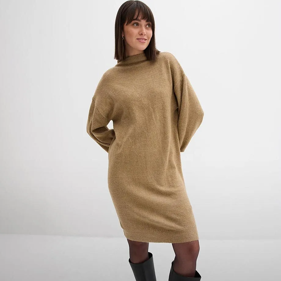Robe en maille douillette de couleur camel, associ&eacute;e &agrave; des collants noirs et des bottes &eacute;l&eacute;gantes.
