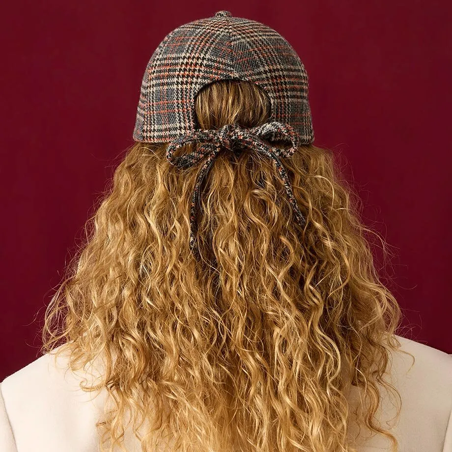 Casquette &agrave; carreaux, manteau cr&egrave;me et pull marron en maille c&ocirc;tel&eacute;e pour un look styl&eacute;.