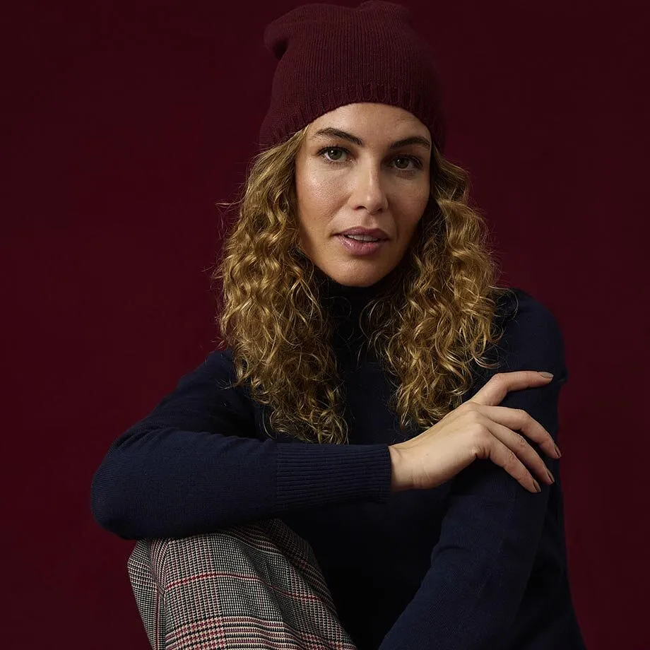 Un bonnet en maille rouge fonc&eacute;, un pull &agrave; col roul&eacute; bleu fonc&eacute; et un pantalon &agrave; carreaux.