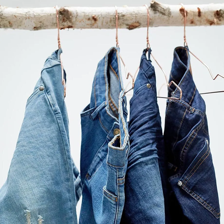 Eine Reihe blauer Jeans in verschiedenen Waschungen h&auml;ngt ordentlich auf Kleiderb&uuml;geln.