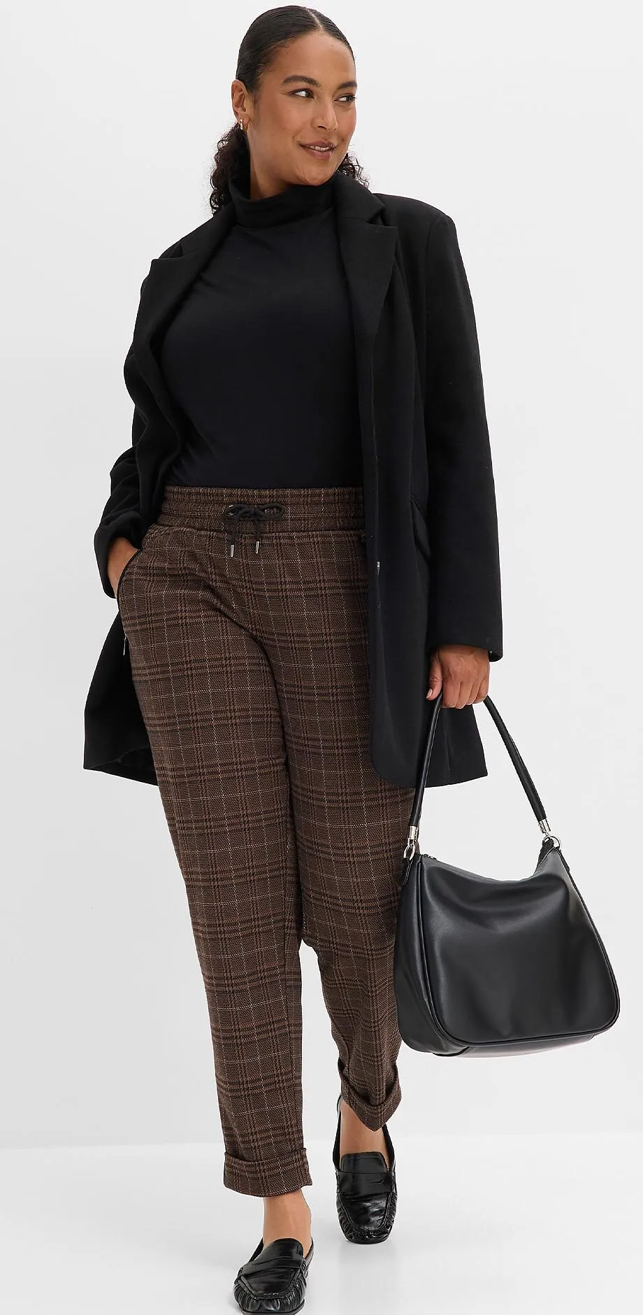 Col roul&eacute; noir, blazer long, pantalon &agrave; carreaux, chaussures &eacute;l&eacute;gantes et sac noir.