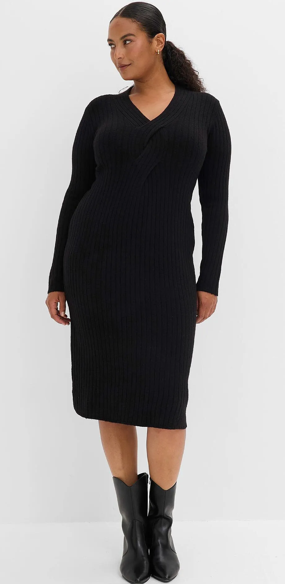 Femme v&ecirc;tue d'une robe en maille c&ocirc;tel&eacute;e noire &eacute;l&eacute;gante et de bottes noires.