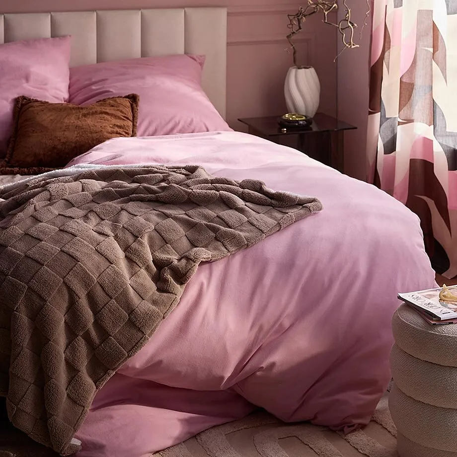 Parure de lit rose et couverture douce marron.
