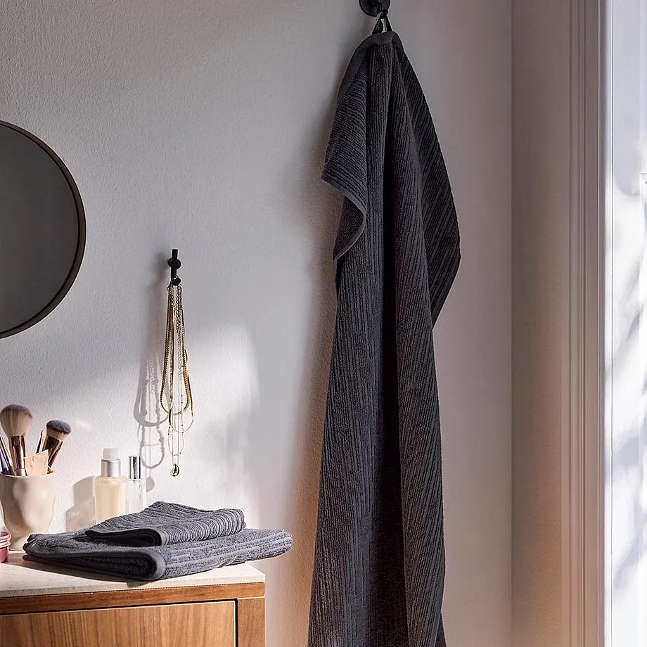 Une grande serviette de toilette grise suspendue dans la salle de bain.