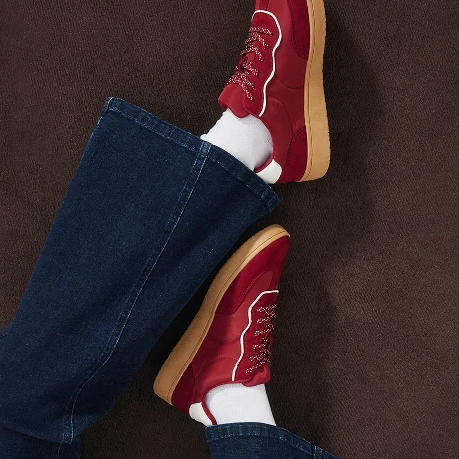 Sneakers rouges, chaussettes blanches et jean bleu fonc&eacute;.