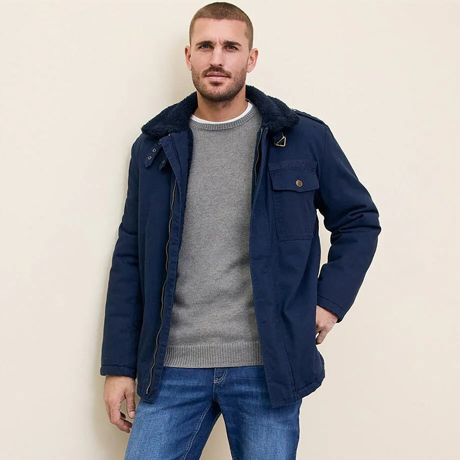 Blaue Jacke, grauer Pullover und Jeans.