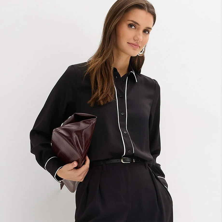 Schwarze Hemdbluse mit wei&szlig;em Kragen, kombiniert mit schwarzer Hose.