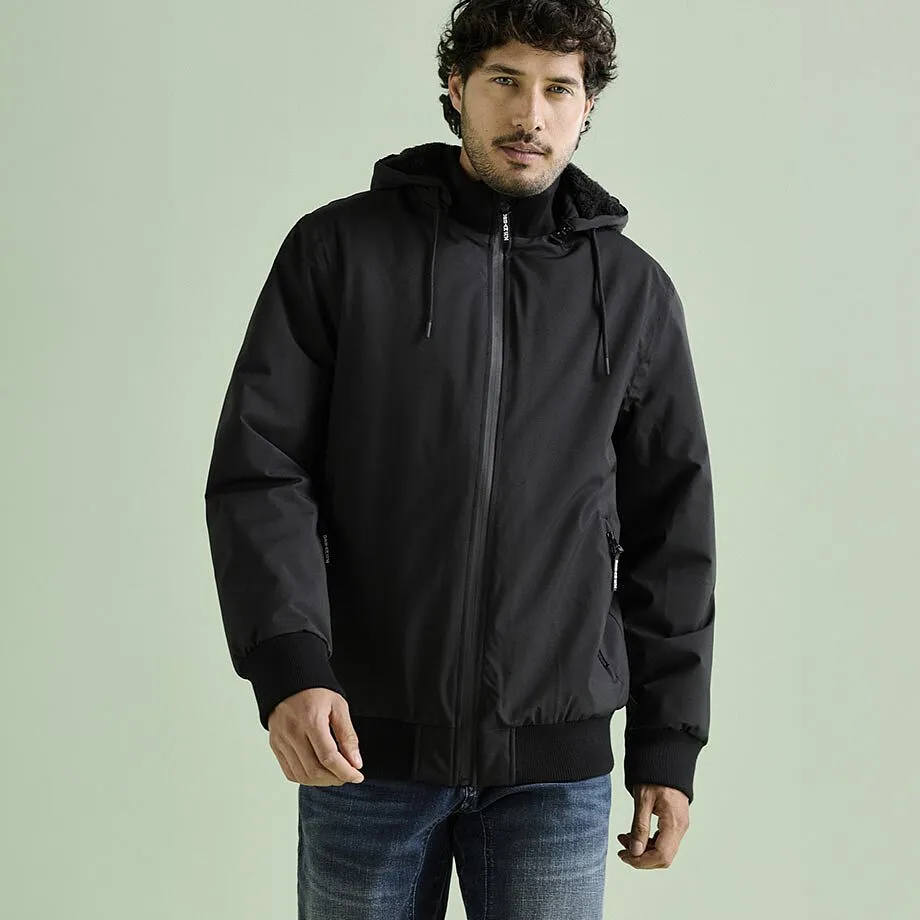 Homme v&ecirc;tu d'une veste noire &agrave; capuche avec fermeture zipp&eacute;e, et d'un jean bleu.