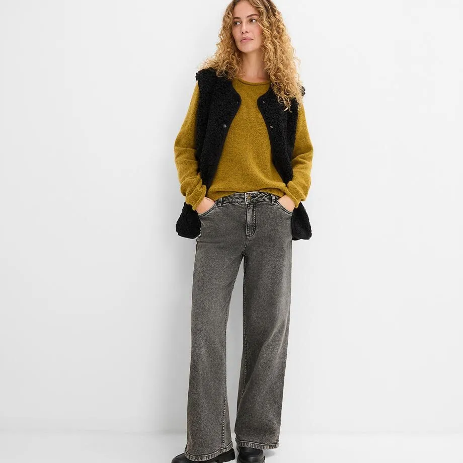  Pull jaune moutarde, gilet noir sans manches et jean gris.