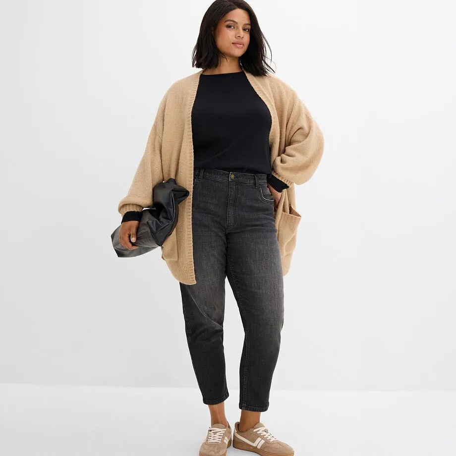 Cardigan en maille beige sur un haut noir, compl&eacute;t&eacute; d'un jean gris et de sneakers beiges.