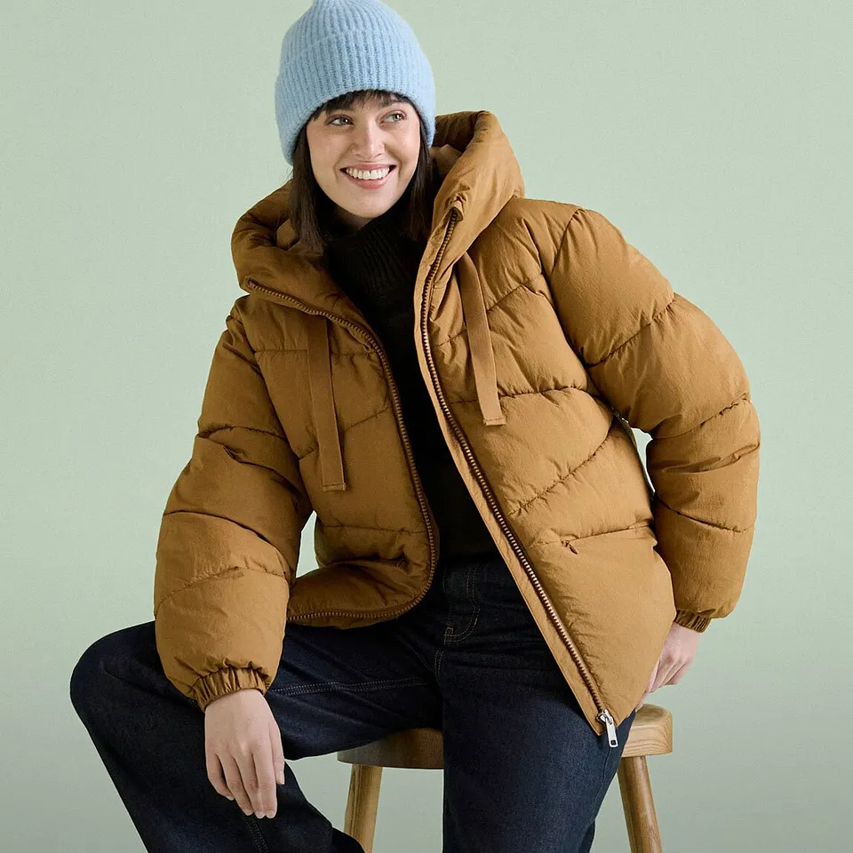 Bonnet bleu, veste matelass&eacute;e marron et jean fonc&eacute;.