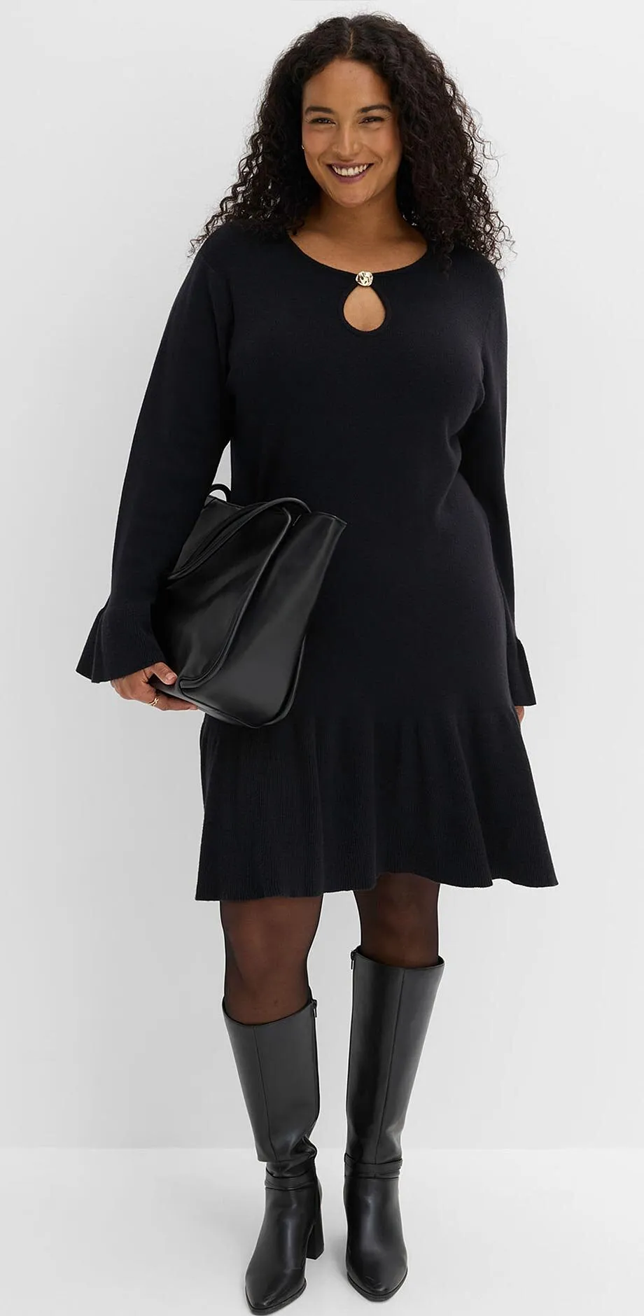 Robe noire &eacute;l&eacute;gante avec d&eacute;coupe au d&eacute;collet&eacute;, collants, bottes &agrave; hauteur de genou et sac &agrave; main.