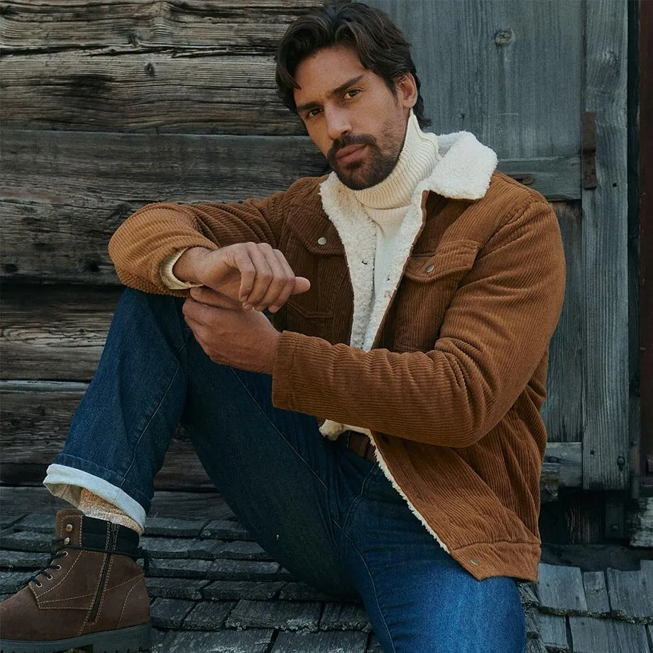 Braune Cordjacke mit Teddyfutter, wei&szlig;er Rollkragenpullover, Jeans und winterliche Boots.