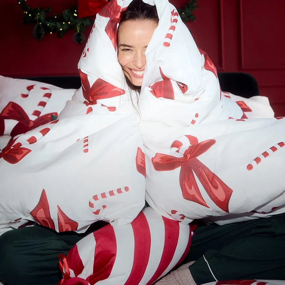 Elle porte un pyjama et s'est envelopp&eacute;e dans une couette aux motifs festifs.