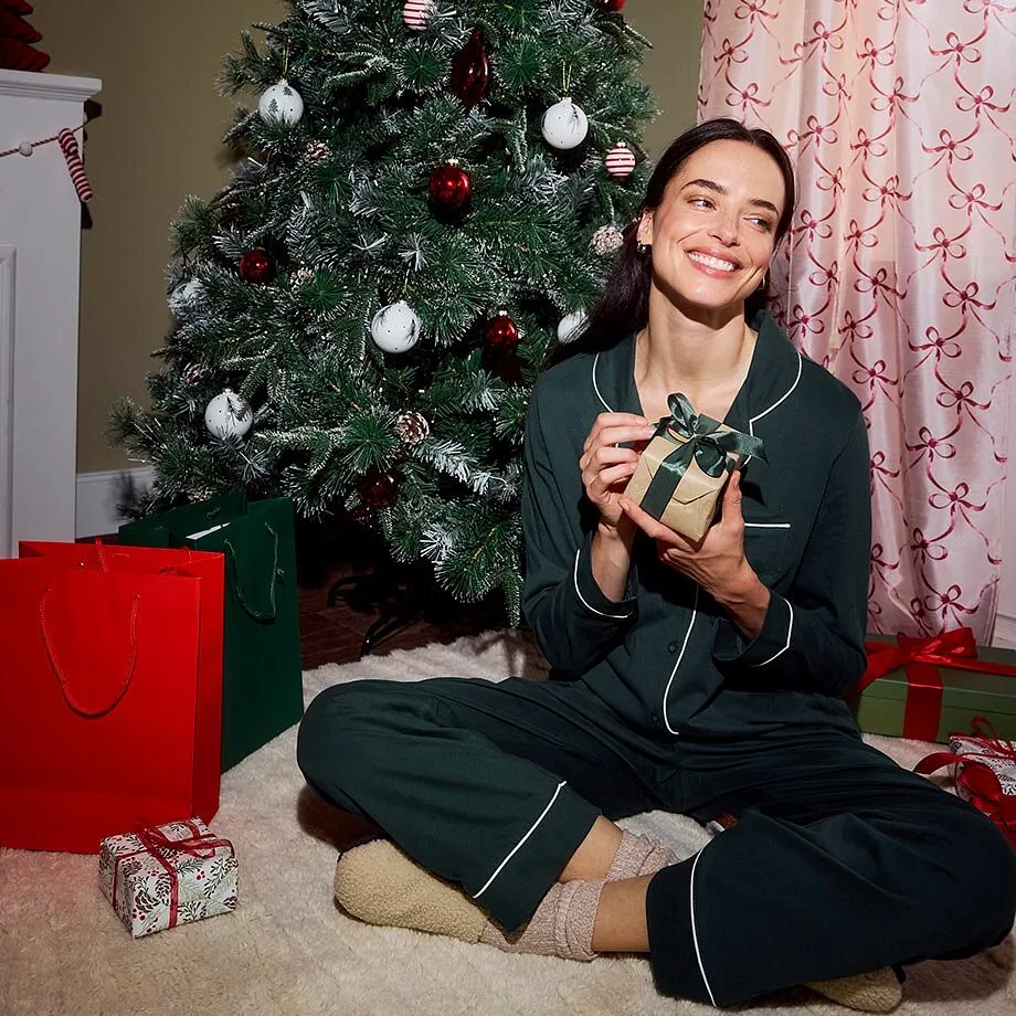 Elle est assise devant un sapin de No&euml;l d&eacute;cor&eacute;.