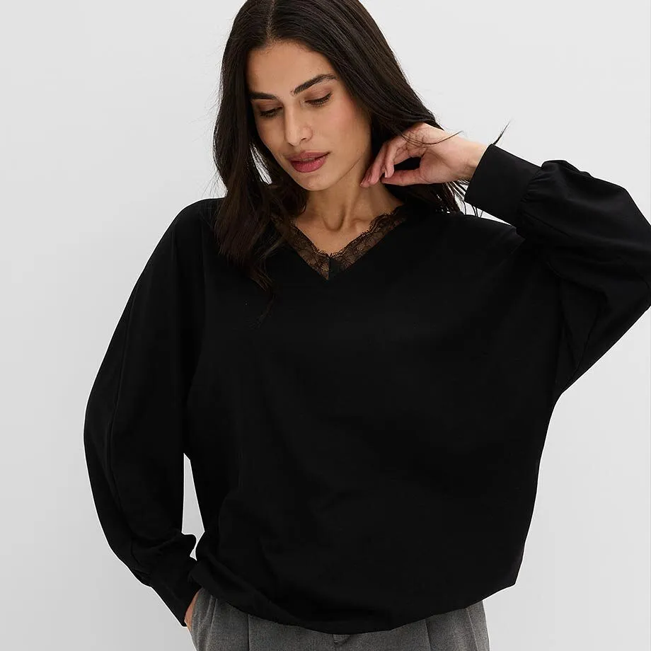 Pull noir chic avec dentelle sur le d&eacute;collet&eacute; et pantalon gris confortable.
