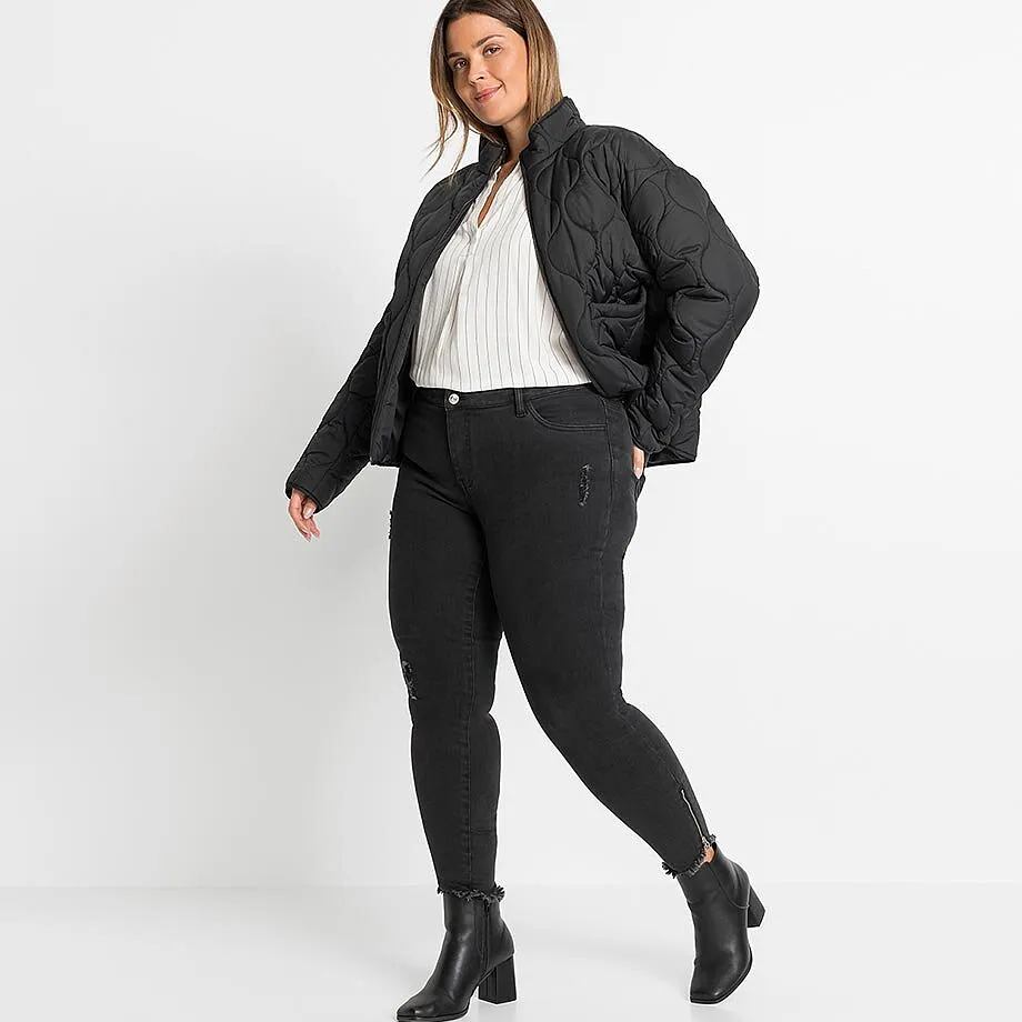 Schwarze Steppjacke, gestreifte Bluse, Jeans mit Rei&szlig;verschl&uuml;ssen und l&auml;ssige Stiefeletten.