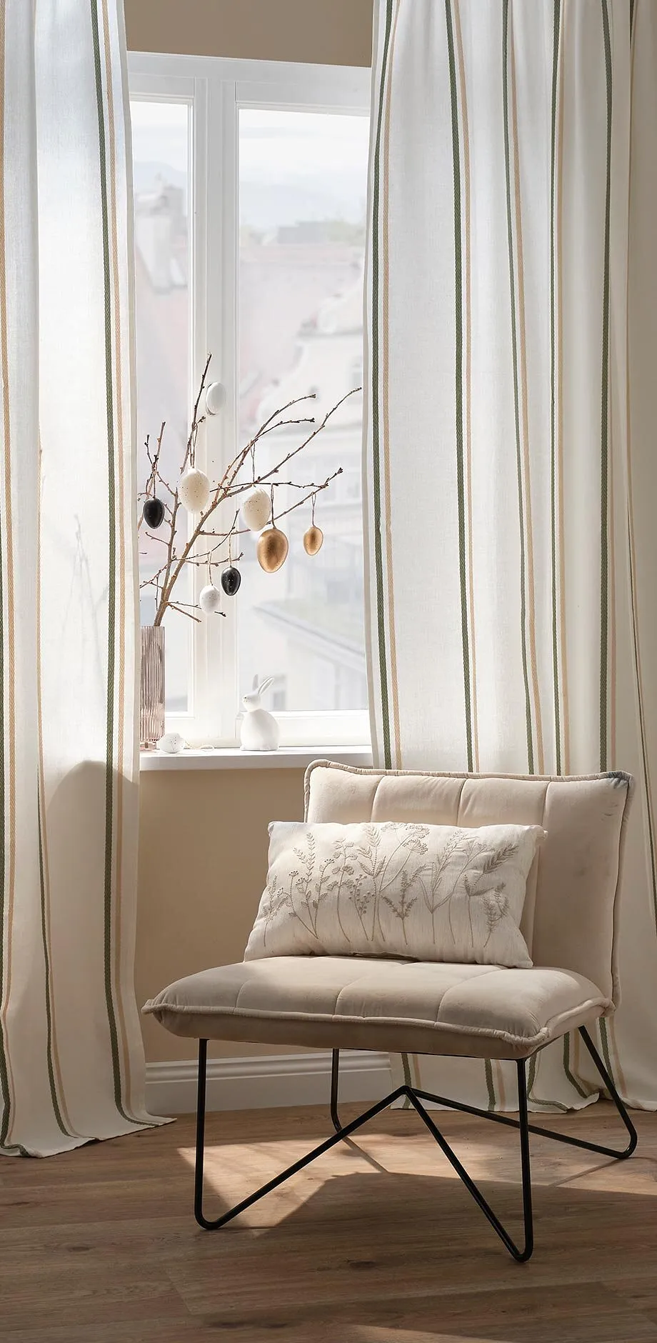 Rideaux &eacute;l&eacute;gants de couleur cr&egrave;me et un fauteuil confortable.