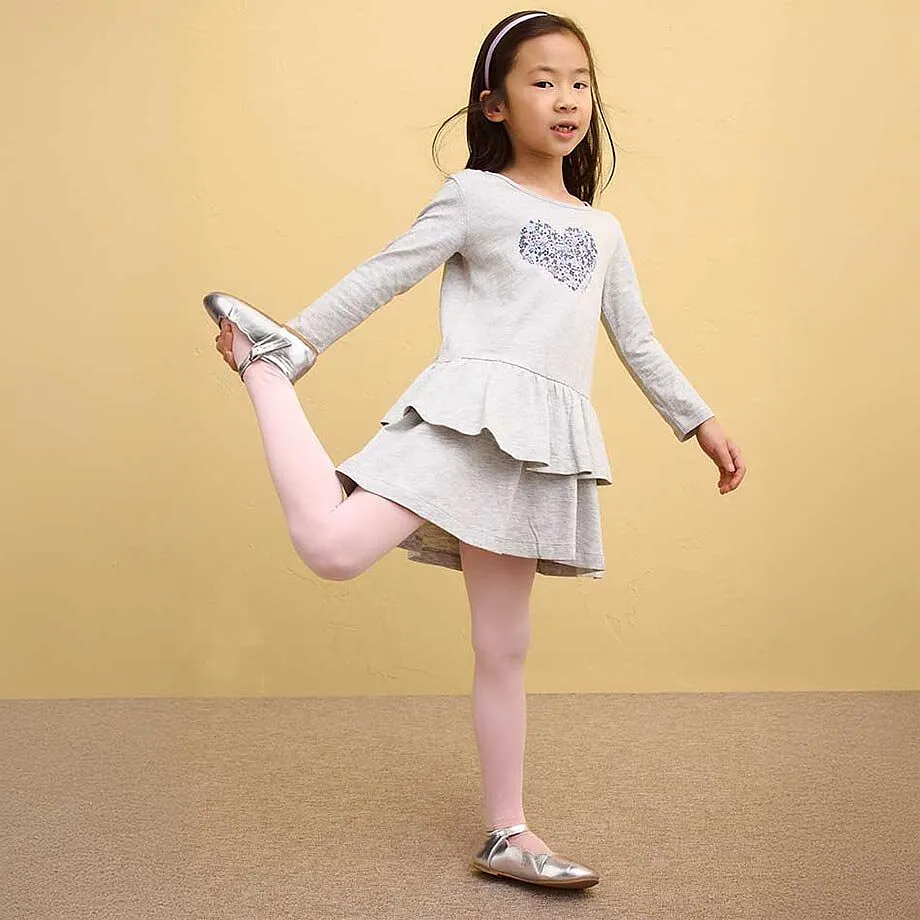 Ein M&auml;dchen tr&auml;gt ein graues Kleid mit R&uuml;schen und rosa Leggings.