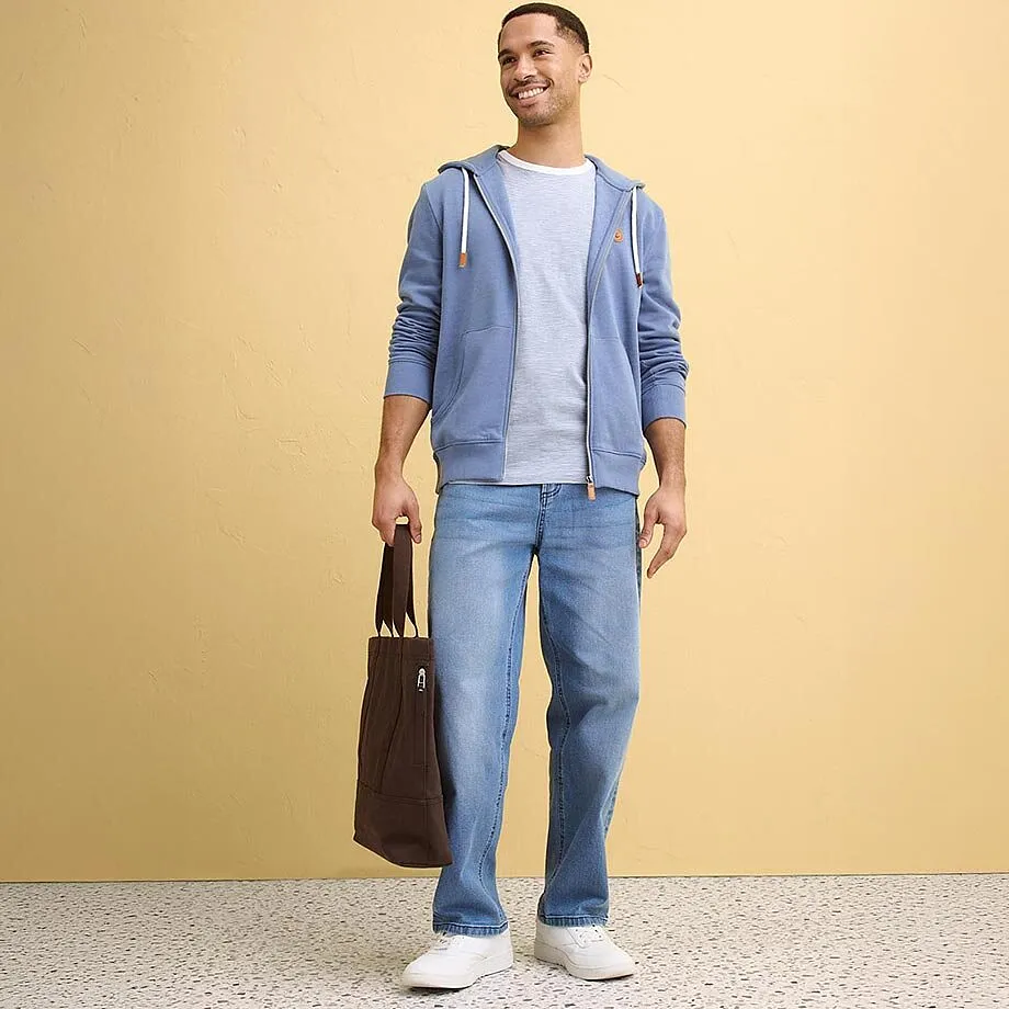 Gilet &agrave; capuche bleu clair par dessus un T-shirt blanc, associ&eacute; &agrave; un jean.