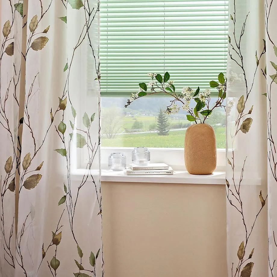 Des rideaux &agrave; imprim&eacute; fleuri d&eacute;corent la fen&ecirc;tre.