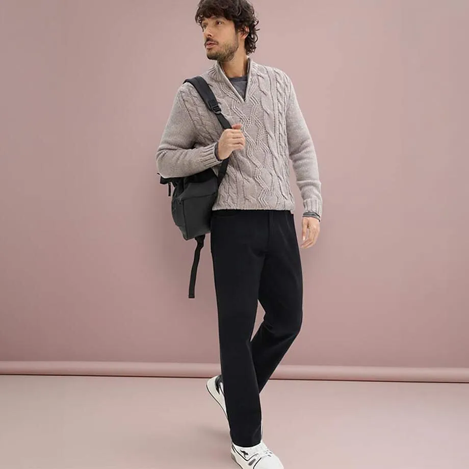 Un pull beige en maille torsad&eacute;e, associ&eacute; &agrave; un pantalon fonc&eacute; en stretch.