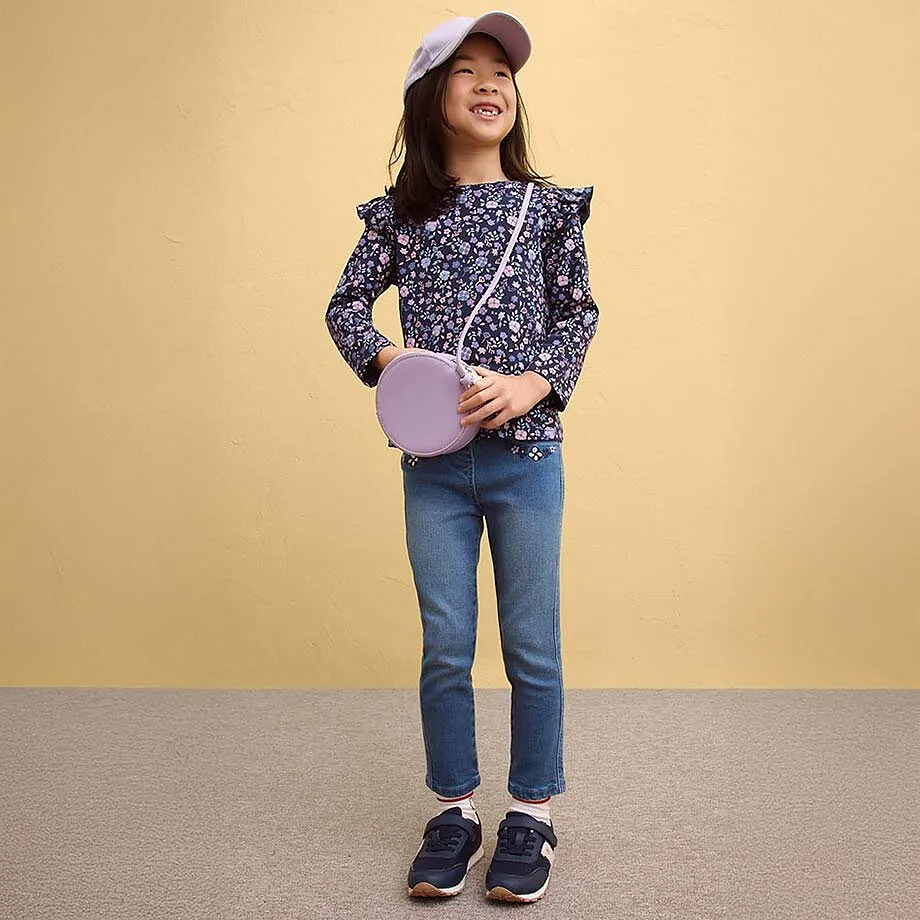 Blouse fleurie &agrave; ruch&eacute;s associ&eacute;e &agrave; un jean et des baskets.