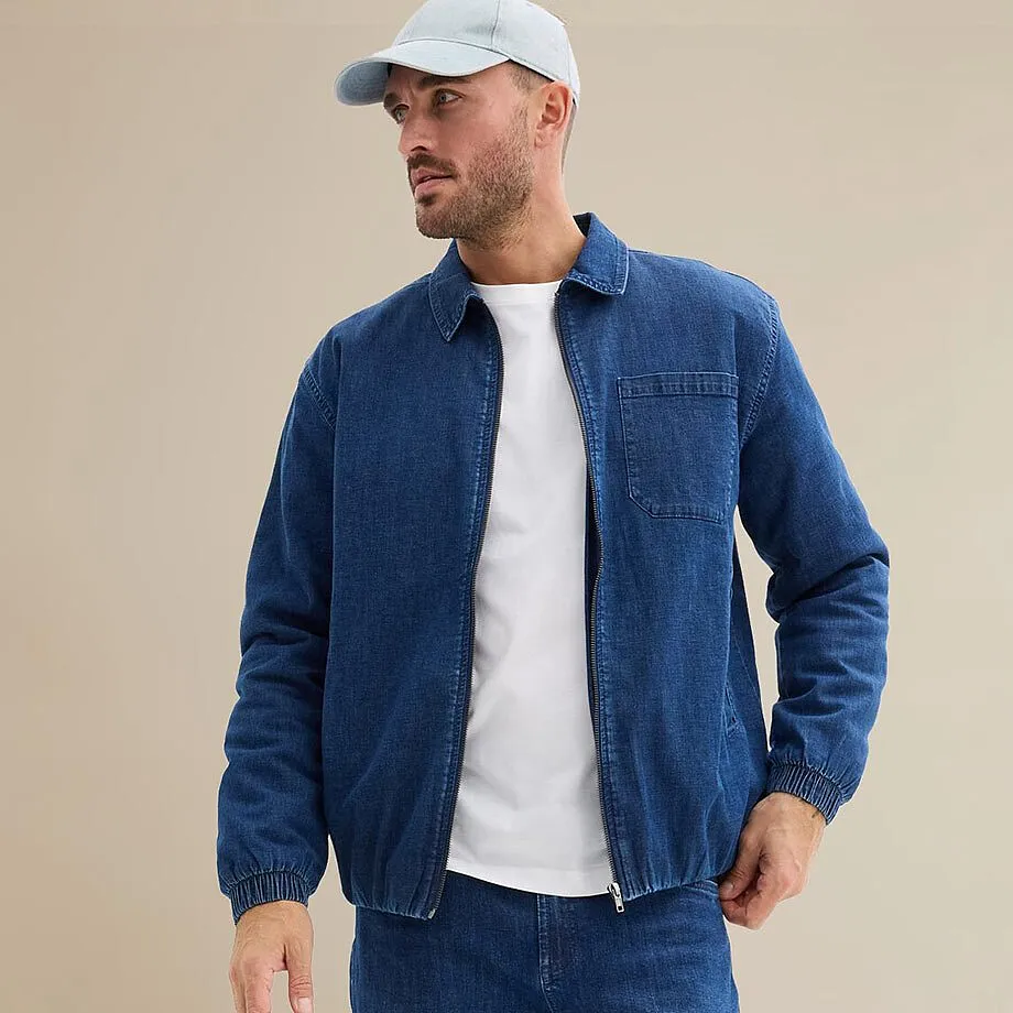 Veste en jean bleu sur une chemise blanche, le tout compl&eacute;t&eacute; par une casquette blanche.