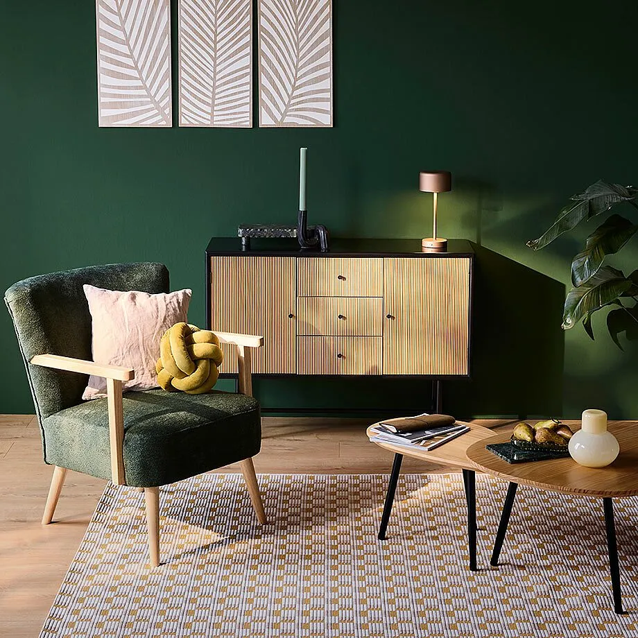 Gem&uuml;tlicher Sessel mit samtigem Gr&uuml;n, warme Holzt&ouml;ne und weiche Textilien.